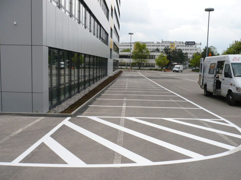 ein Parkplatz mit weißen Linien und einem Gebäude im Hintergrund