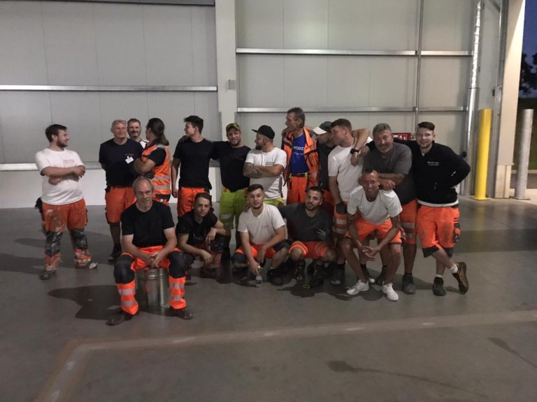 Männer mit orangenen Arbeiterhosen posieren für ein Foto