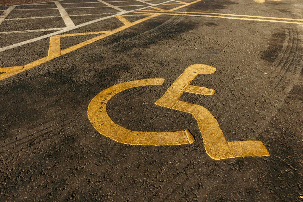 Bodenmarkierungen für Parkplätze sind wichtig, so wie das Behindertenschild in gelb auf diesem Bild, welches eine barrierefreie Parkplatzmarkierung zeigt
