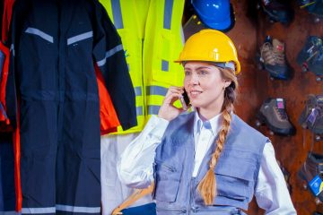 Telatisnki_Kontakt_Startseite Eine Frau telefoniert mit Bauarbeiterhelm auf einer Baustelle