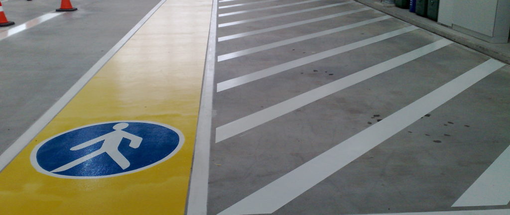 eine Nahaufnahme von Bodenmarkierungen mit weißen Streifen und einem blauen Gehweg Schild