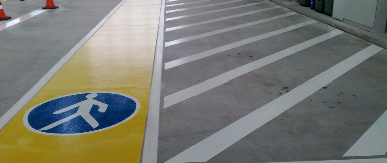 eine Nahaufnahme von Bodenmarkierungen mit weißen Streifen und einem blauen Gehweg Schild