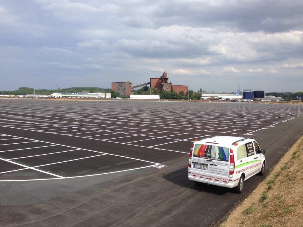 Parkplatzmarkierungen und ein weißer Lieferwagen auf einem großen Parkplatz