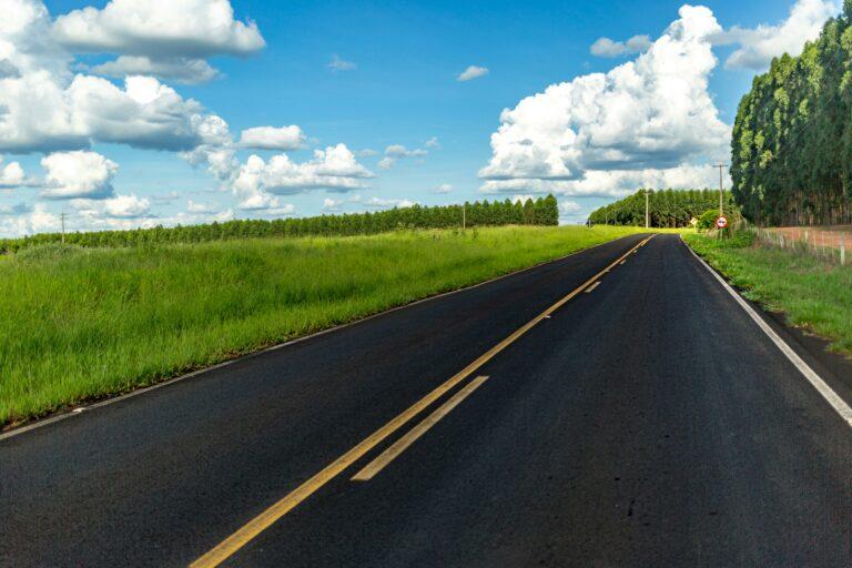 Straßenmarkierung in gelb entlanf einer Straße unter blauem Himmel mit weißen Wolken